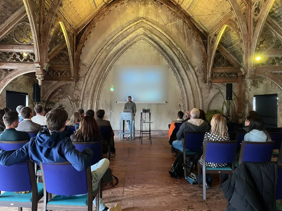 Frank de Jongh giving a talk to an audience in a historic hall